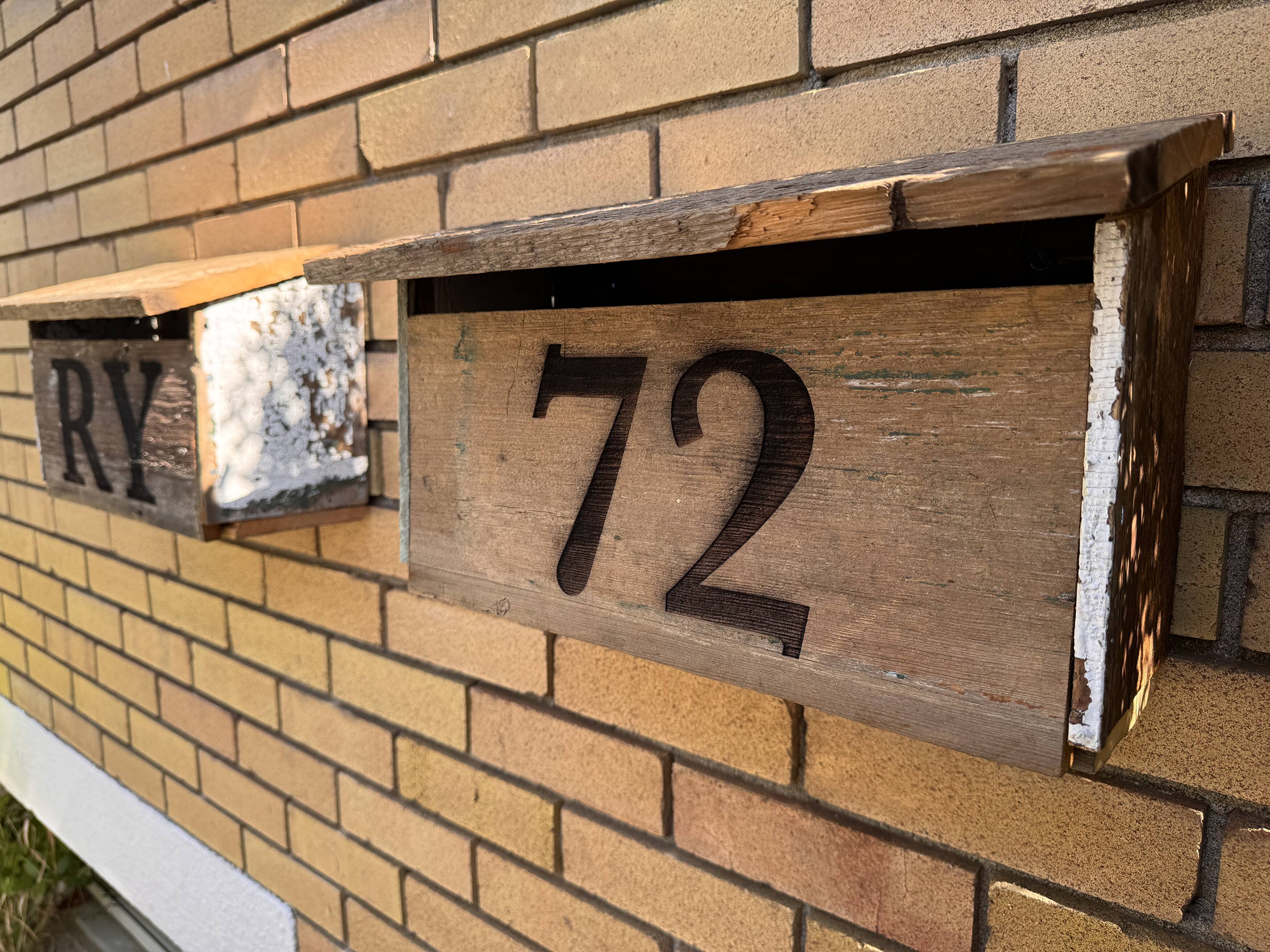 Custom wooden address sign mounted on brick